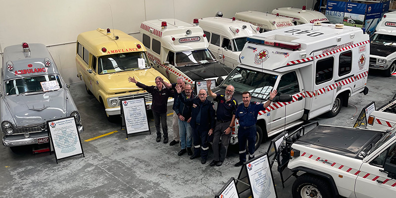 51 Museum's volunteers standing together in the museum's garage where a variety of vintage ambulances are kept.