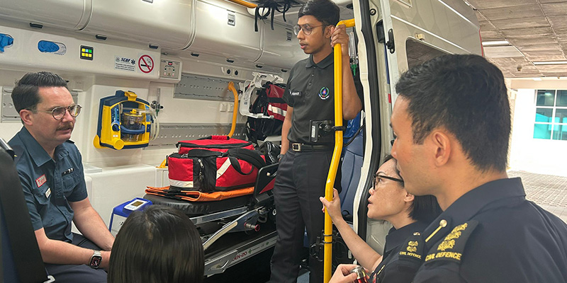 51 Medical Director Associate Professor David Anderson speaking to a number of Singapore Civil Defence Force personnel from inside an ambulance during his visit to Singapore in 2023.